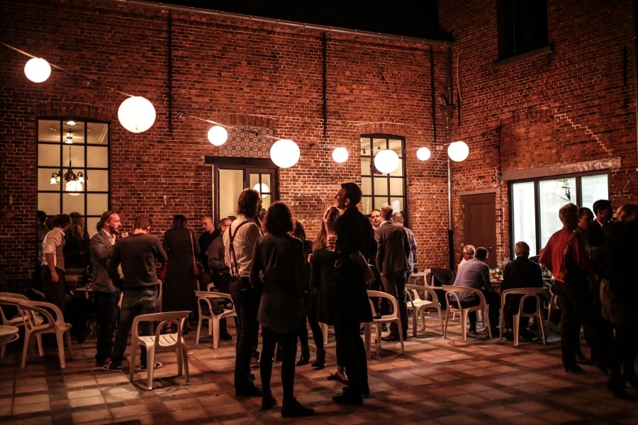 Mensen die socialiseren in een industriel restaurant of café met een rode bakstenen muur, rondhangende lampen en witte stoelen.