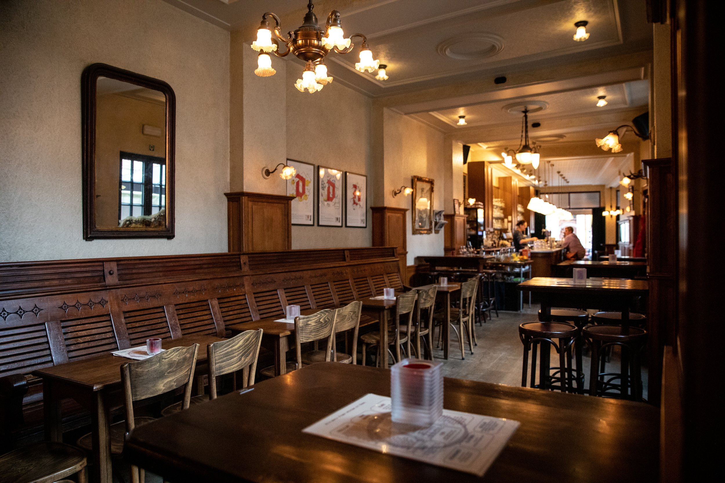 Binnenkant van een gezellige restaurant of café met houten meubilair, spiegels en lichtarmaturen, klaar voor gasten